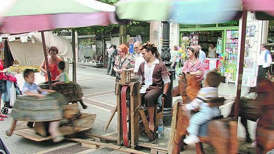 Varios niños, disfrutando en un tiovivo de madera a pedales.