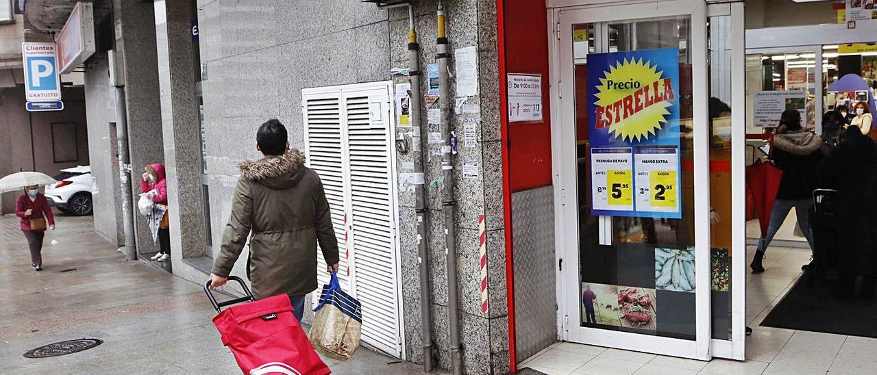 Un joven sale de un supermercado de Vigo tras realizar unas compras. |   // ALBA VILLAR