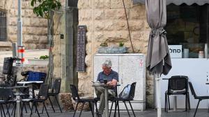 Un hombre lee en la terraza de un café de Jerusalén, este domingo, tras el ataque sin precedentes de Irán de la pasada noche.