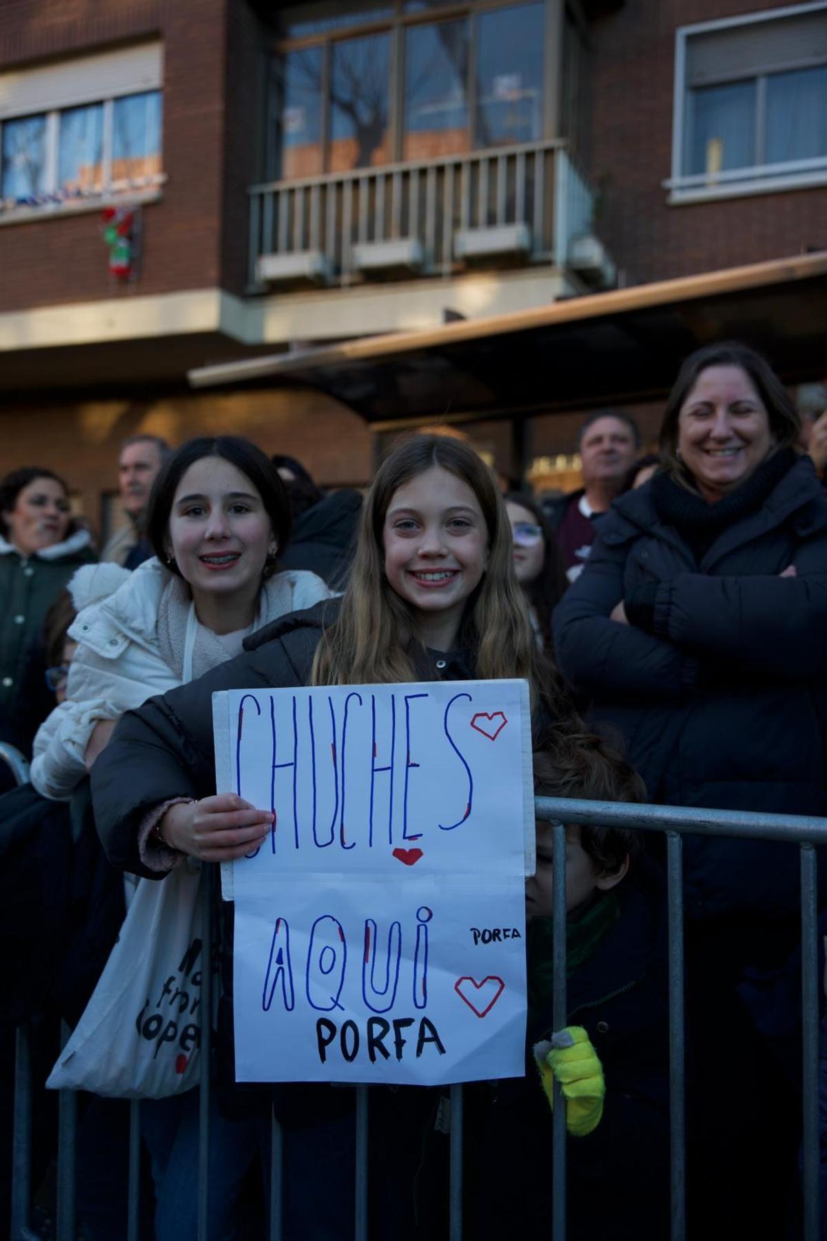 Un niña muestra un cartel durante el desfile en el que pide golosinas.