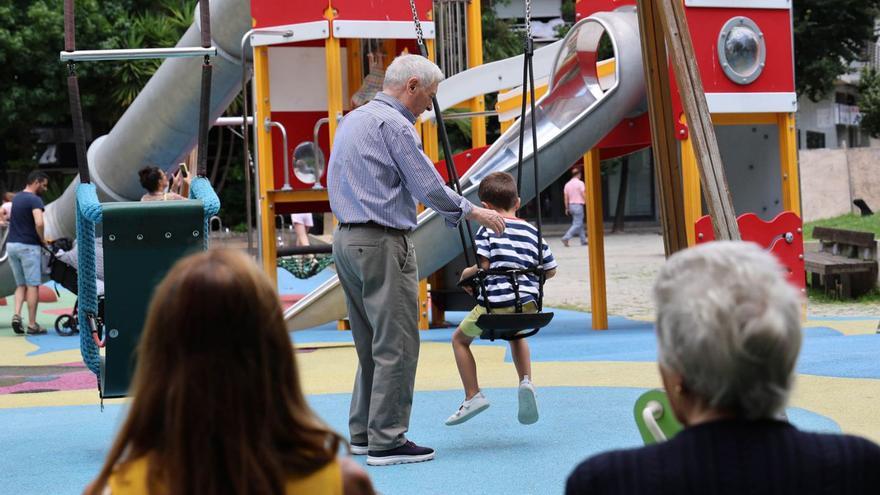 Un abuelo empuja a su nieto en un columpio en la plaza de la Independencia de Vigo.