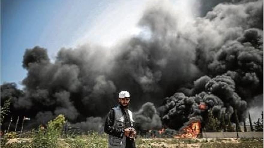 Un home palestí camina davant la negra columna de fum, a la zona central de la franja de Gaza