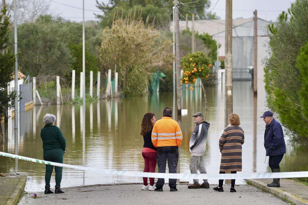 Varios vecinos conversan junto a un área inundada en la zona rural de las Pachecas, en Jerez de la Frontera (Cádiz) por el desbordamiento del río Guadalete