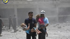 Voluntarios de la Defensa Civil con niños, tras un bombardeo en Daraa.