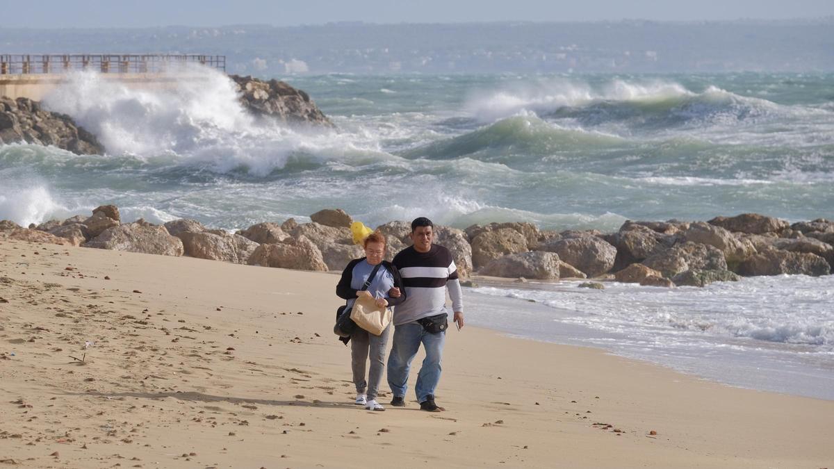 Una pareja pasea por la playa de Can Pere Antoni con el Portitxol al fondo.