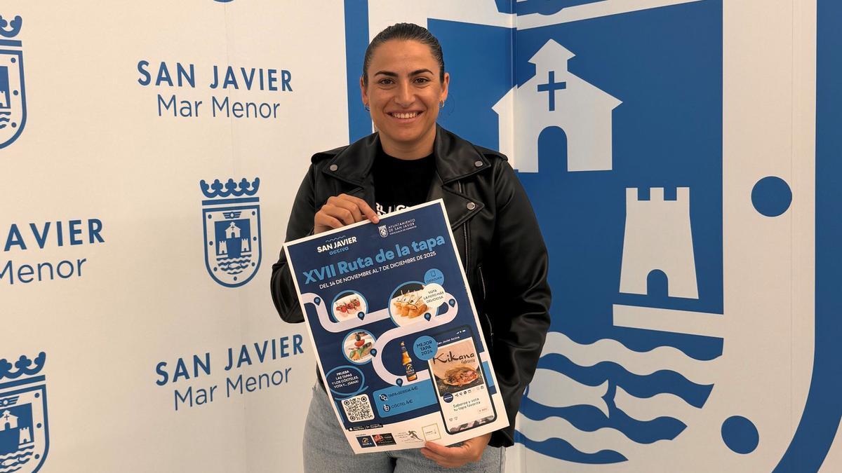 La concejala de Comercio, Isabel Madrid, muestra el cartel anunciador de la nueva edición de la Ruta de la Tapa de San Javier