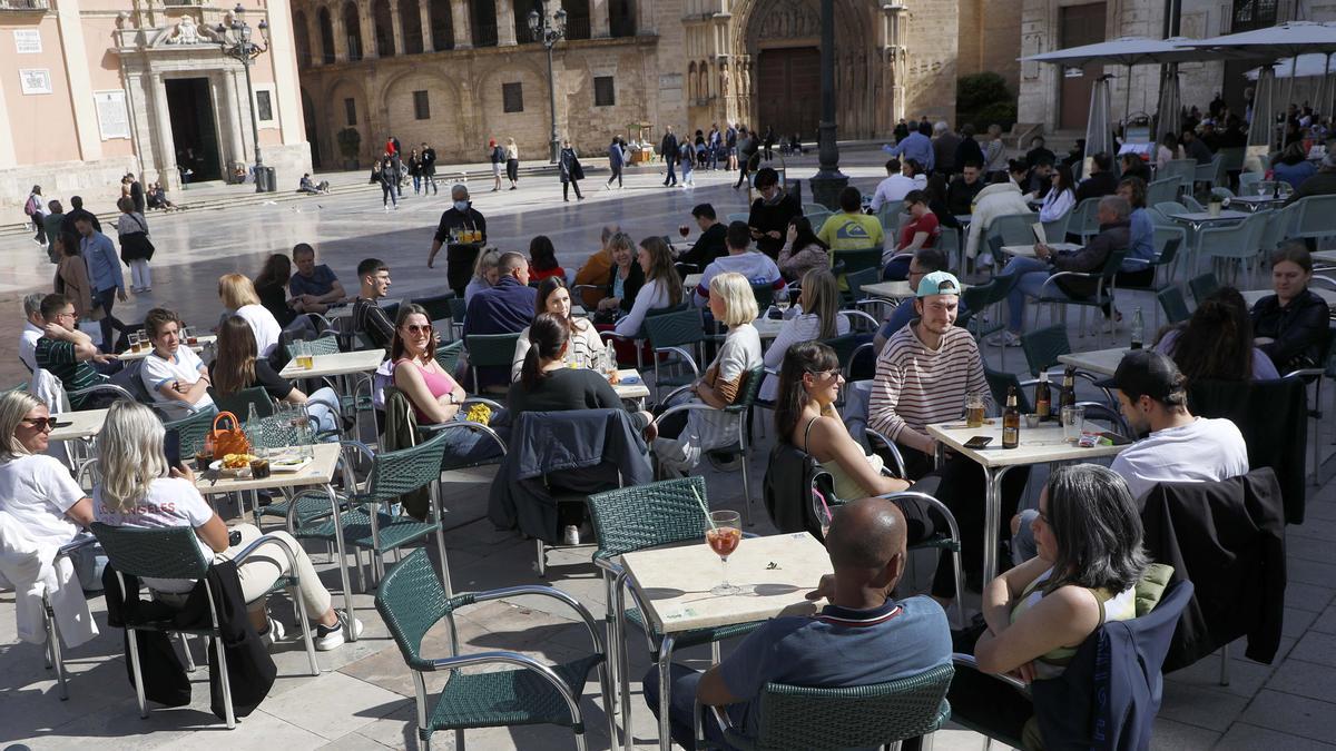 Gente disfrutando del sol en las terrazas de la plaza de la Virgen de València, este verano.
