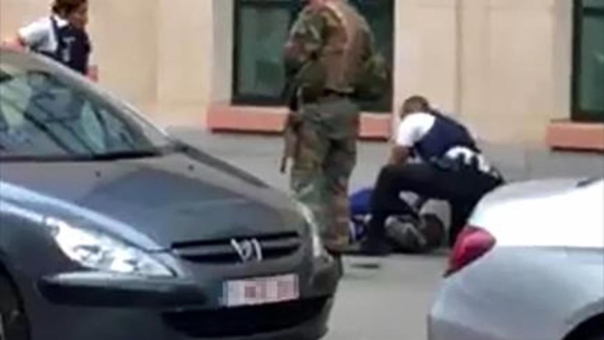 Dos policías y un militar, junto al hombre abatido ayer en Bruselas.