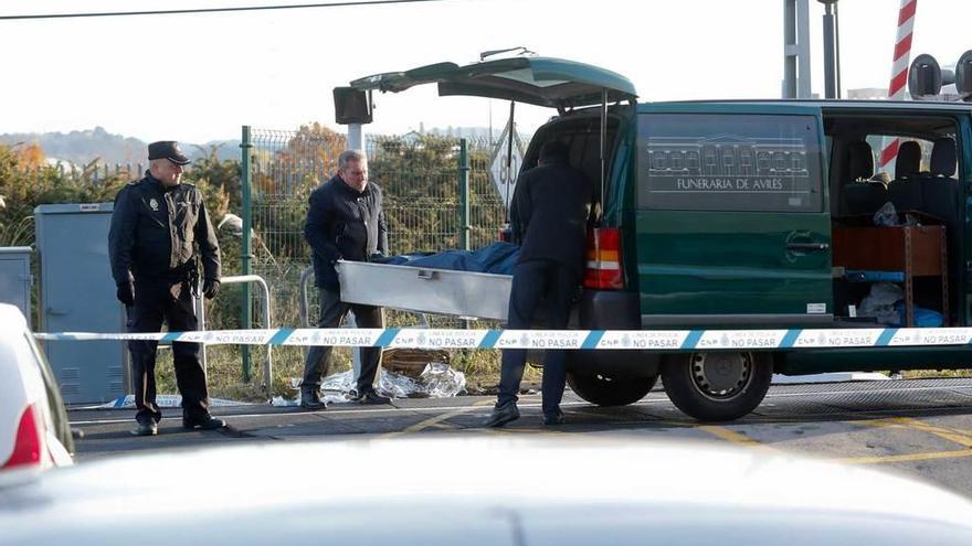 Responsables de la funeraria trasladan el cadáver en una zona acordonada por la Policía Nacional en el apeadero.