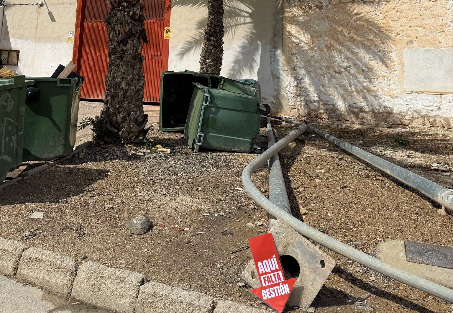Uno de los carteles que señala en la calle las deficienas. En este caso un almacén de báculos de alumbrado y contenedores