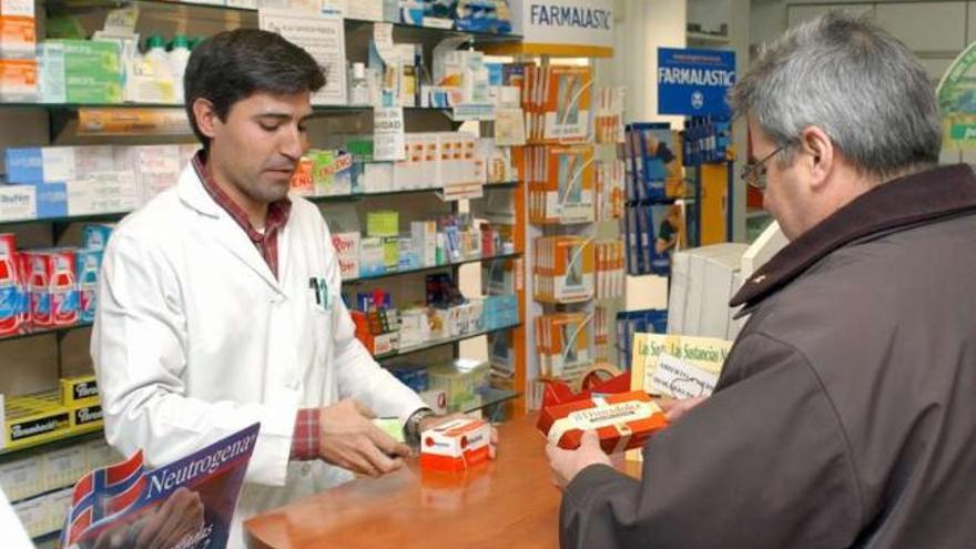 Un farmacéutico atiende a un cliente en su establecimiento. / efe