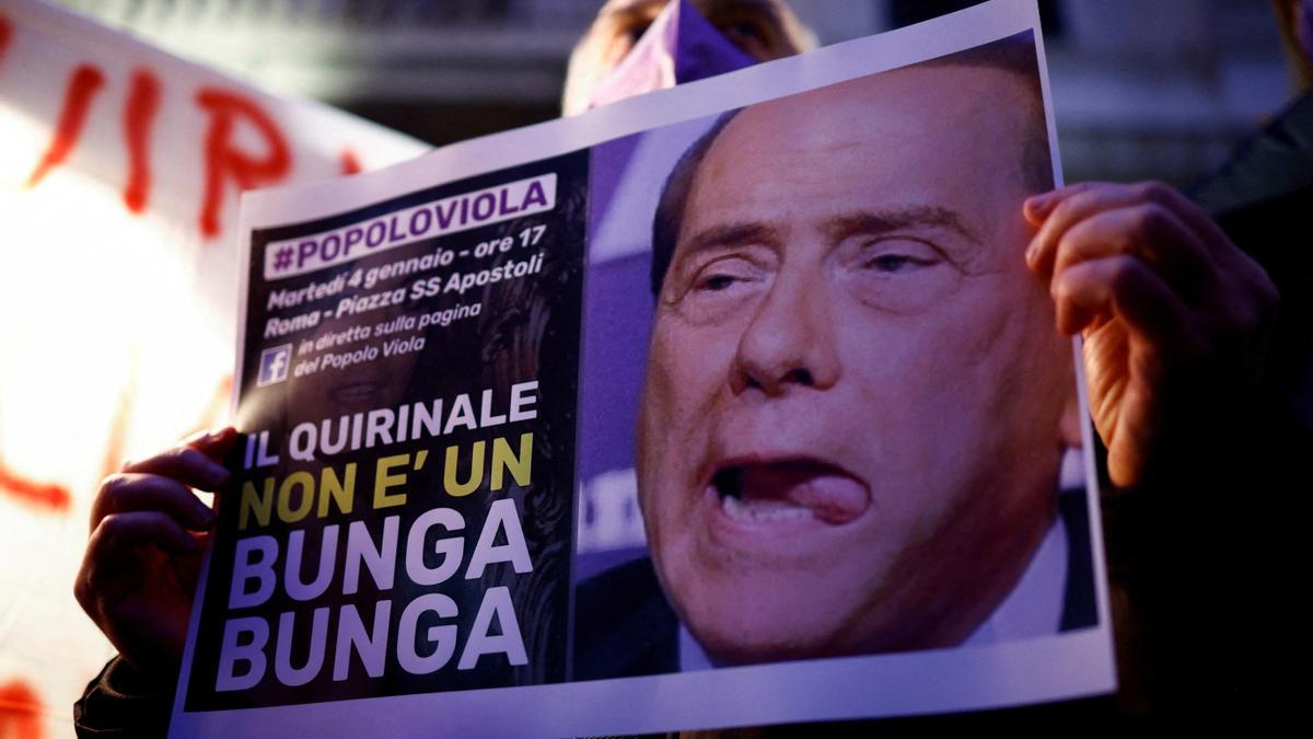 Un hombre sostiene un cartel contra Silvio Berlusconi.