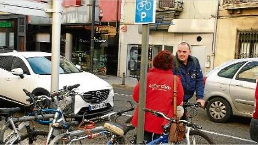 Una agent cívica informa un usuari de bicicleta a Olot de les normes que cal respectar.