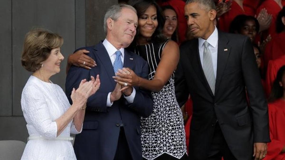 La primera dama, Michelle Obama, abraza al expresidente George Bush, en el momento de llegar con Obama a la inauguración del museo de África inaugurado en Washington.