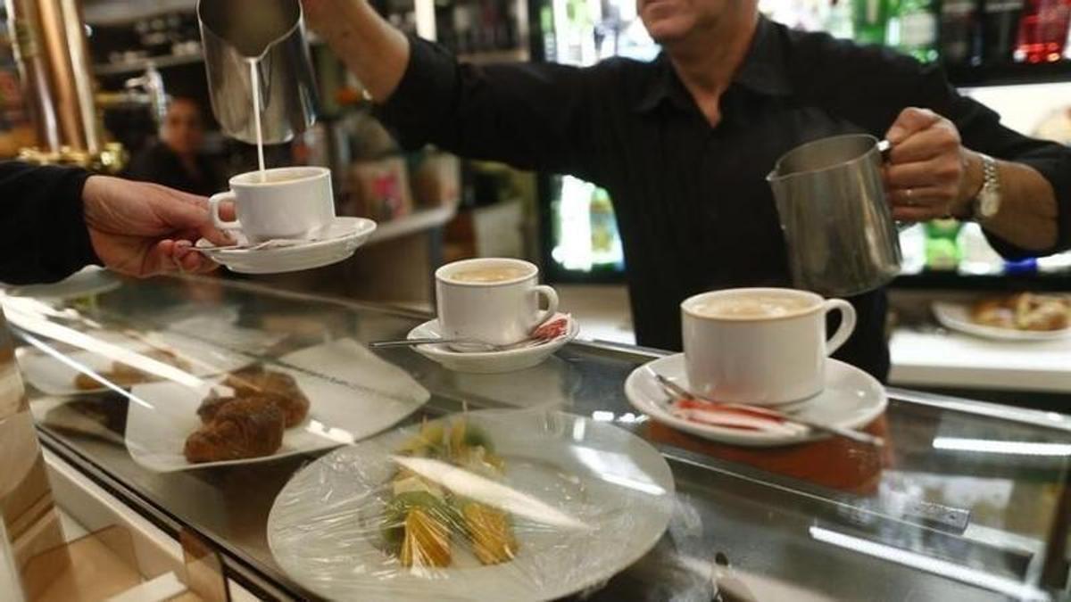El gerente de un bar sirve un café en la barra de su establecimiento.