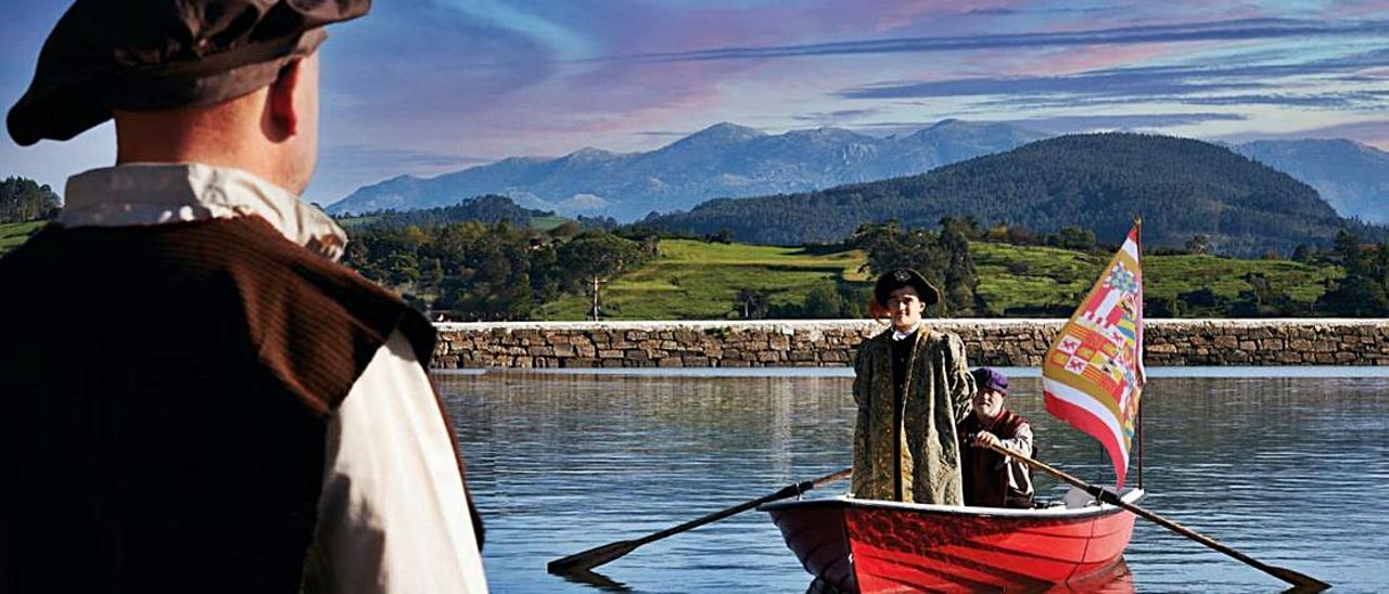 Juan Ángel Merino (de espaldas), en una de las imágenes del calendario, contempla desde  la orilla la llegada de Carlos V (Manuel Domínguez) para su desembarco en Villaviciosa.  En el bote, remando, Carlos Rojo. | Reproducción de Paula Fernández