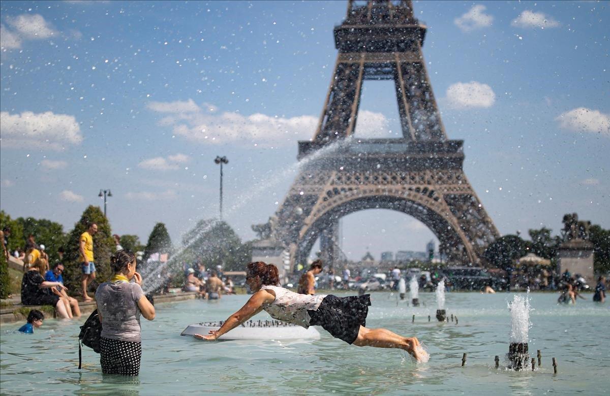 Una mujer se refresca con el agua de la fuente de la Plaza del Trocadero, frente a la Torre Eiffel, durante la ola de calor que recorrió París el pasado junio.