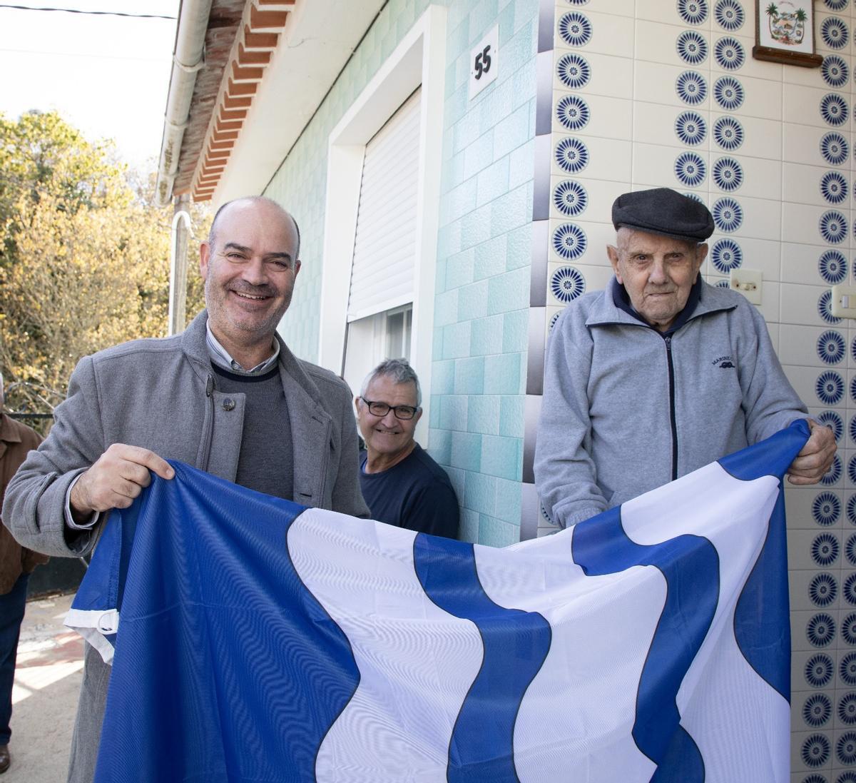 El alcalde de Bueu, Félix Juncal, le entrega a José Otero Estévez una bandera del Concello de Bueu como regalo por sus 100 años.