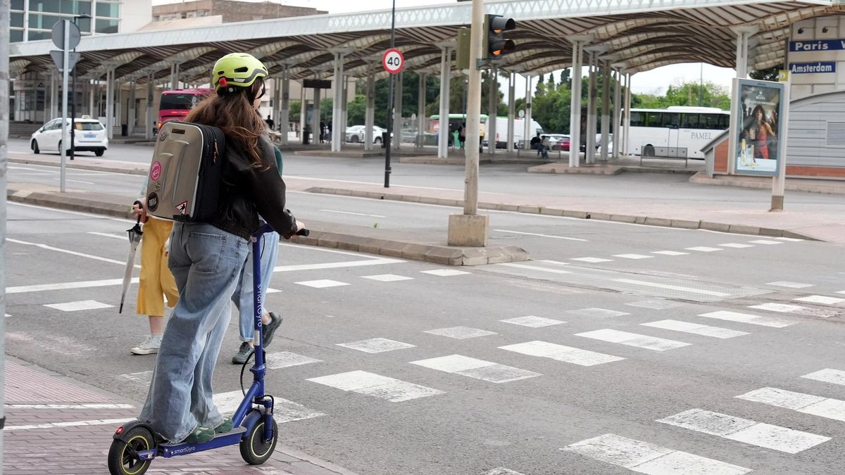 Una chica se dispone a cruzar una calle en un patinete eléctrico.