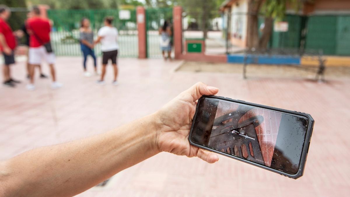 Una persona muestra la foto de la jeringuilla aparecida en un banco junto al colegio.