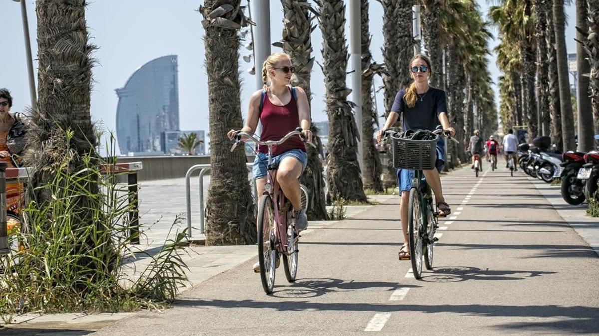 Unas ciclistas circulan por el carril bici que transcurre frente a la Vila Olímpica.