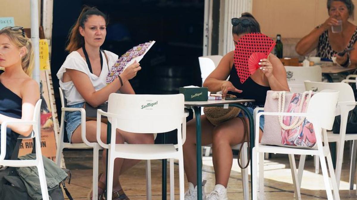Dos mujeres combaten el calor en Málaga con sendos abanicos.