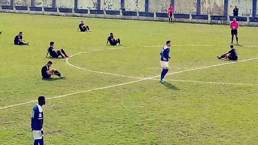 Los jugadores del Avilés, a la izquierda, sentados nada más iniciarse el partido de ayer.