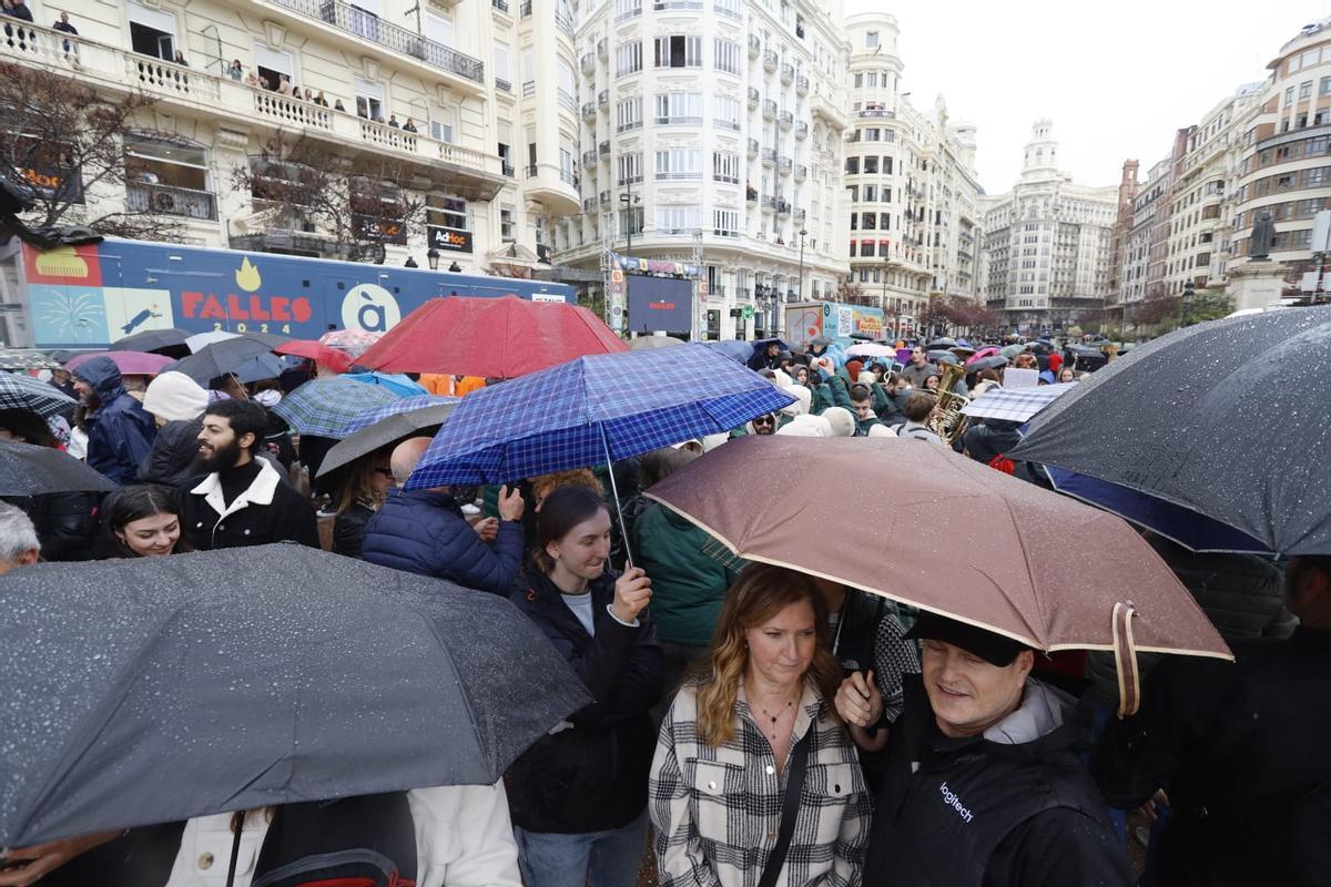 Gente con paraguas en la plaza del Ayuntamiento para la mascletà
