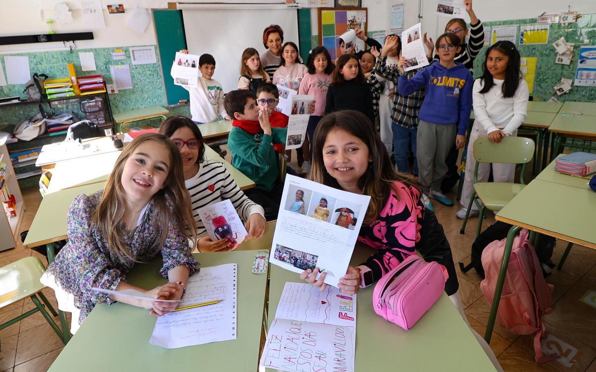 Algunos de los escolares que participan en el proyecto con su maestra, enseñando cartas que remitirán a los mayores.