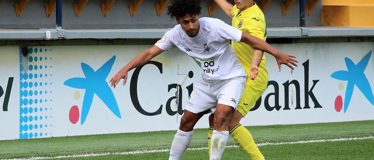 El futbolista del Olímpic aguanta el balón ante la presión del jugador del Villarreal C.