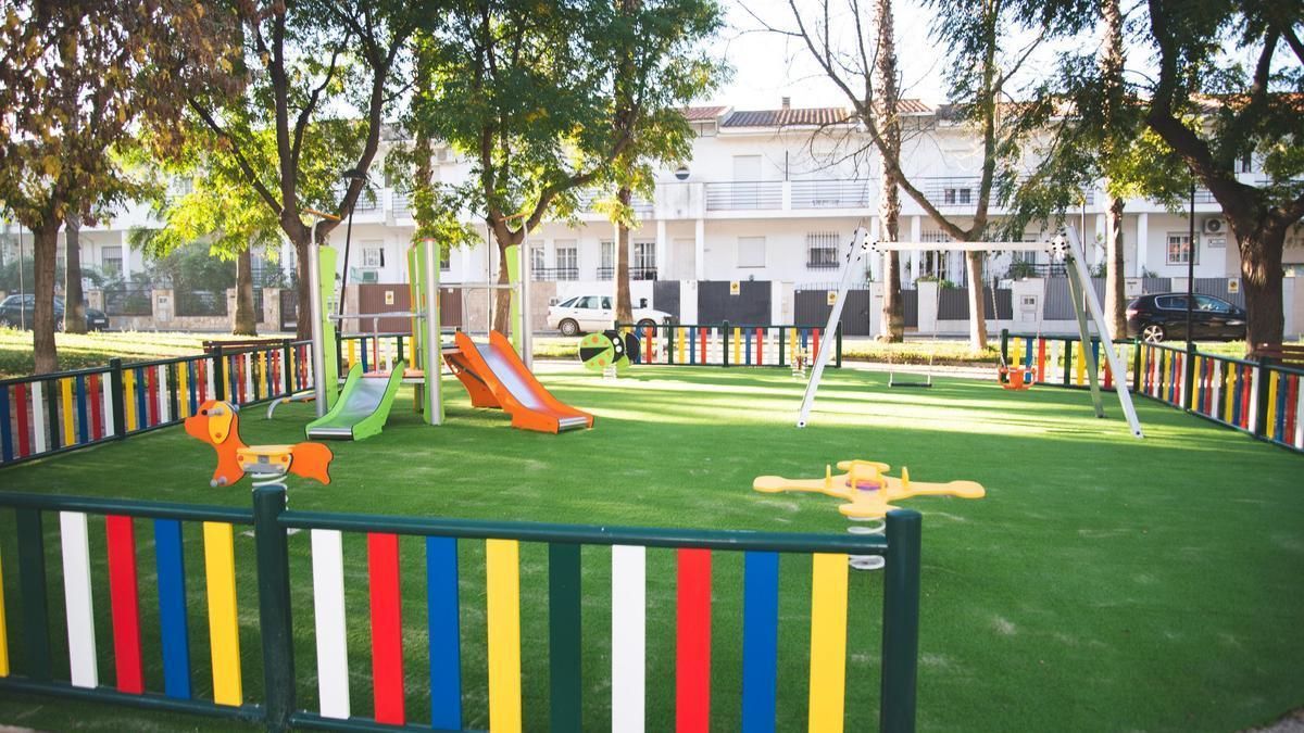 Un parque infantil con césped y valla perimetral, como tendrán los de Plasencia.
