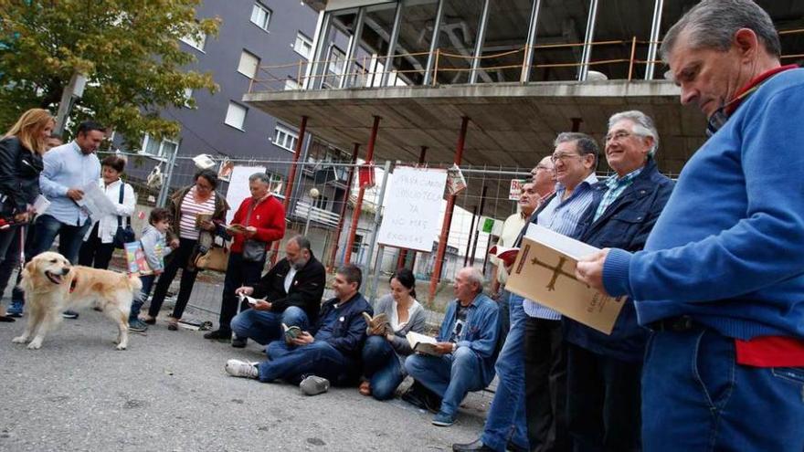 Afiliados y simpatizantes de IU, ayer, concentrados delante de las obras de la biblioteca, y, al fondo, las vallas con libros y pancartas colgando.