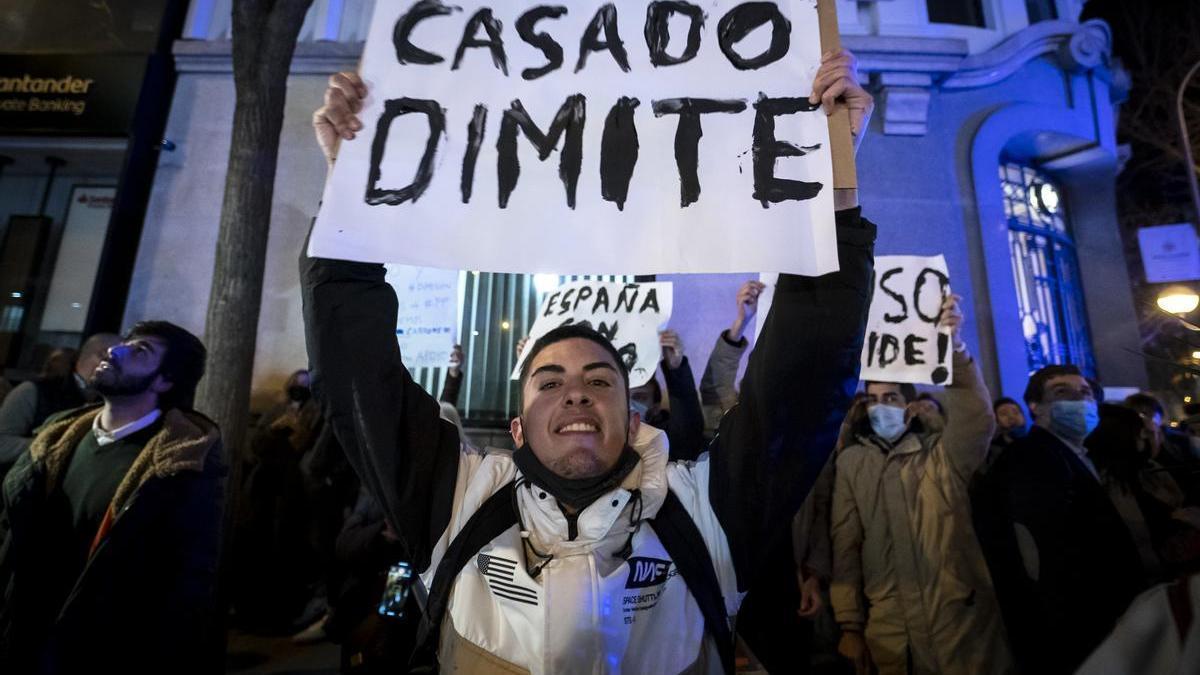 Un simpatizante de Ayuso sostiene un cartel contra Pablo Casado en una concentración en Génova.