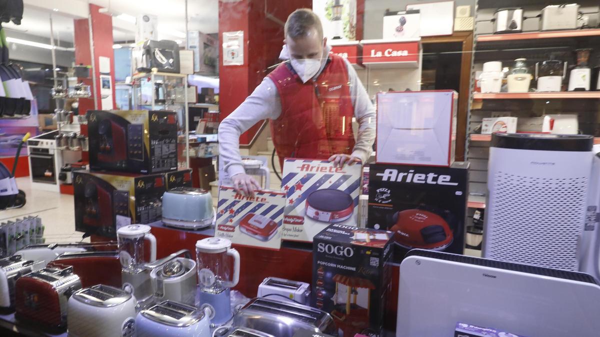 Un comerciante coloca un producto en el escaparate en la víspera de Reyes, en un negocio de la avenida de la Argentina, en La Calzada.