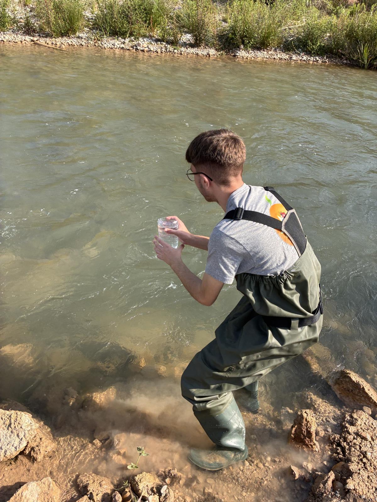 Un alumne de l'IES El Quint de Riba-roja prenent una mostra d'aigua del riu Túria per tal d'analitzar-la.