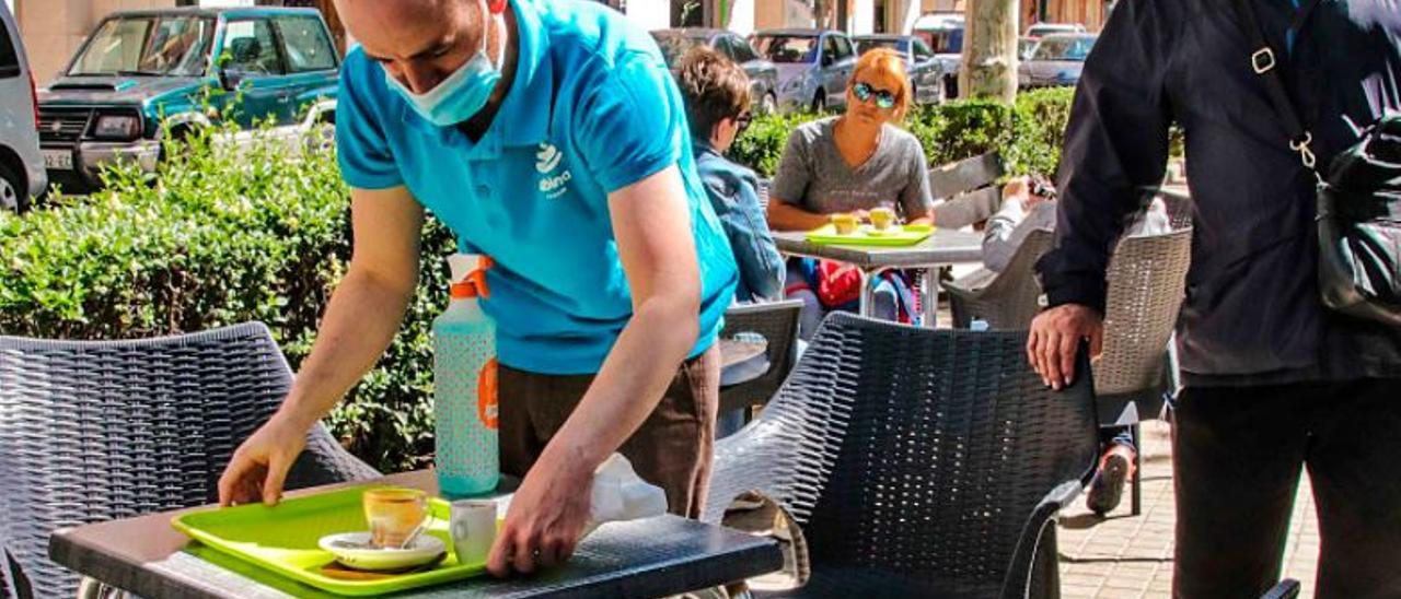 Un profesional de la hostelería recoge una mesa.