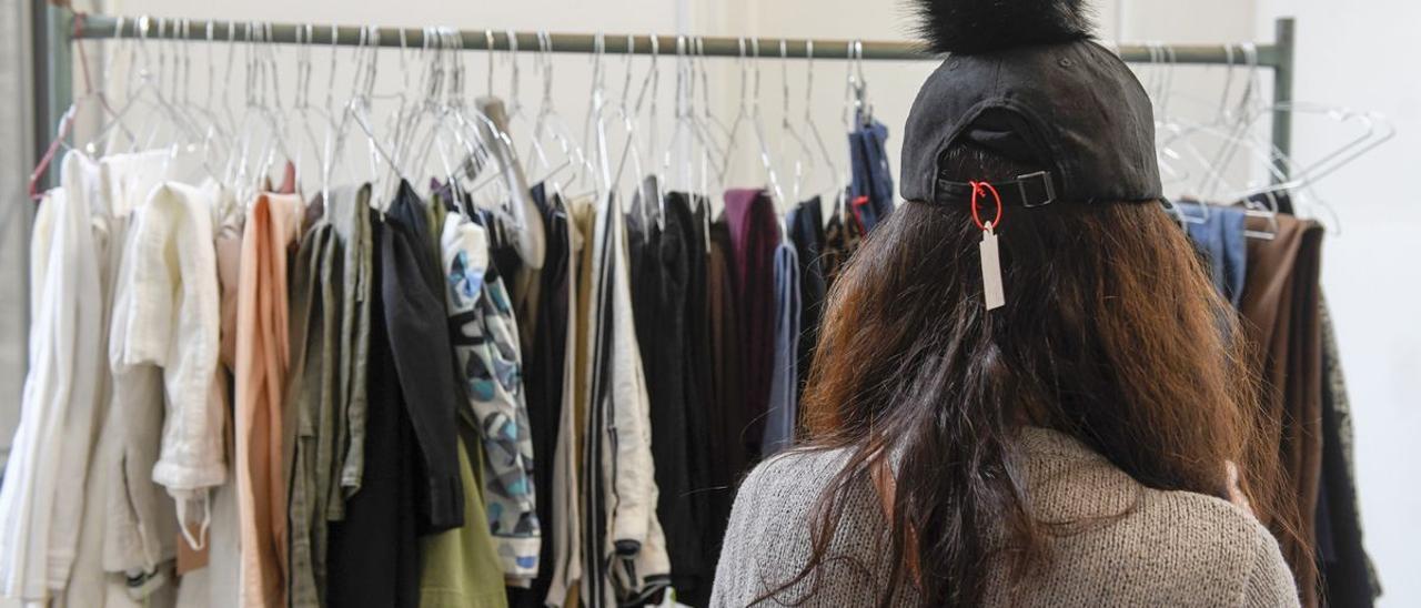 Una mujer acude al mercadillo 'baúl weekend' de ropa de marca de segunda mano donada.