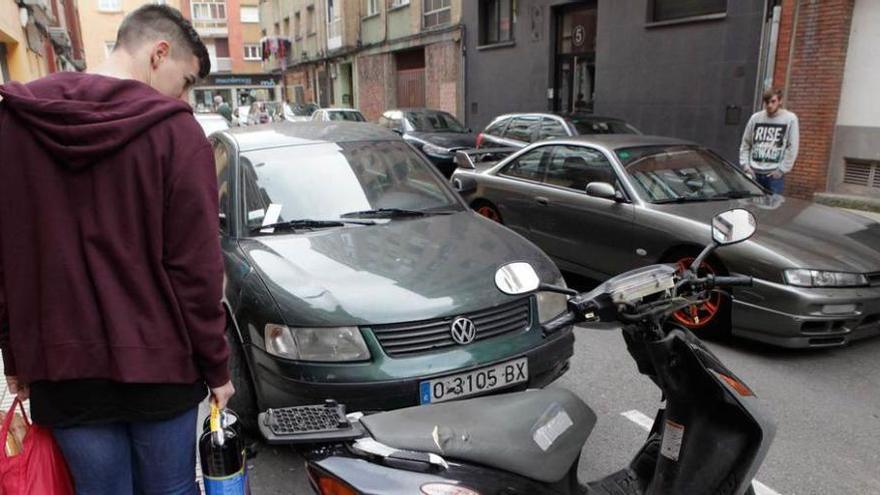 Un joven observa los daños en un coche en La Calzada.