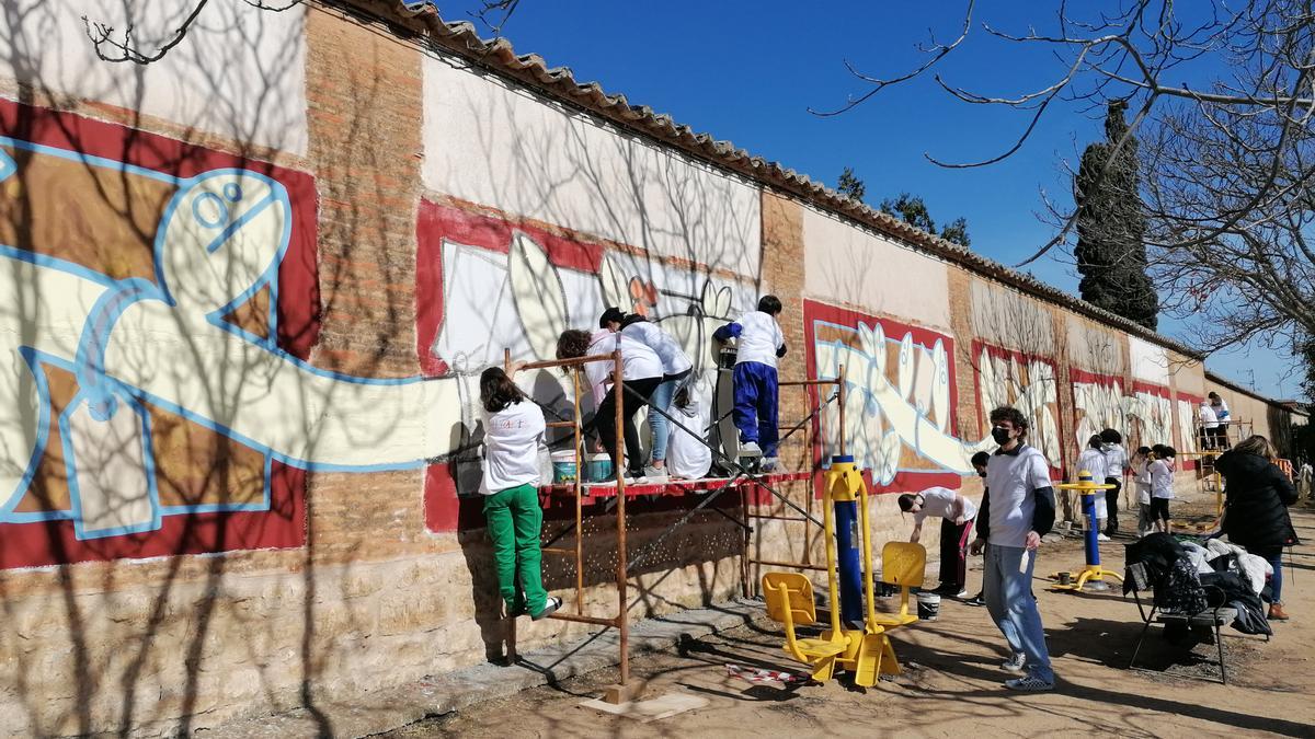 Jóvenes trabajan en la creación del mural en una tapia del convento de las Carmelitas