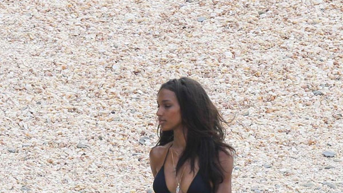 Jasmine Tookes andando por la playa con un bikini negro
