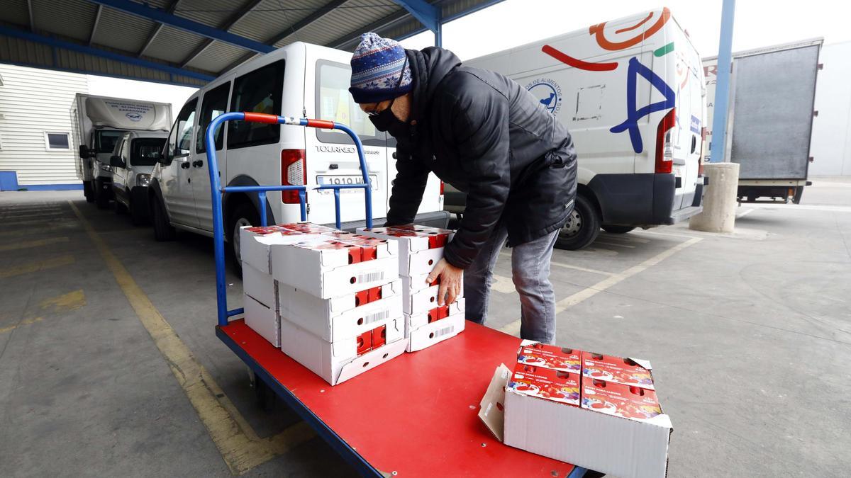 Un voluntario transporta alimentos donados en una carretilla.