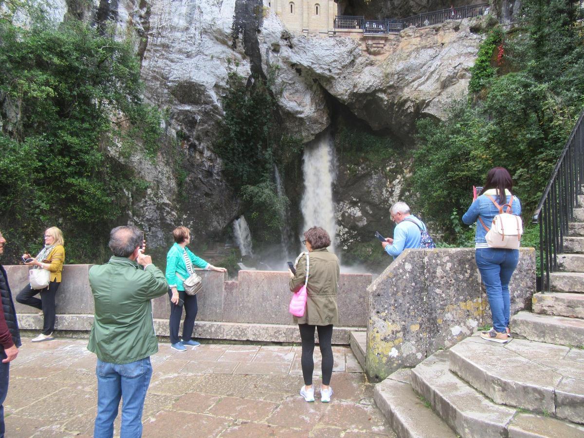 Excursionistas toman fotos del "chorrón" de la cueva de la Santina.