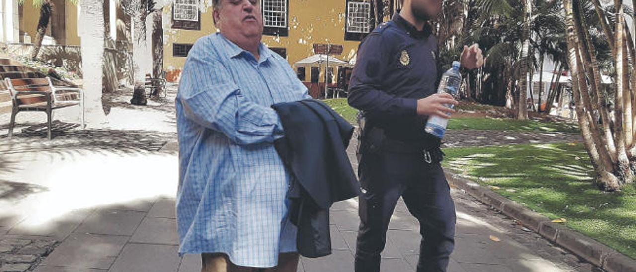 Evaristo González Reyes sale esposado y escoltado por un policía de la sede del TSJC en la plaza de San Francisco de Santa Cruz de Tenerife.