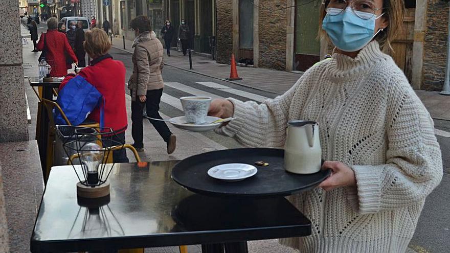 La hostelera Marta Pérez recoge una mesa de las tres que tiene disponibles en su terraza, en una de las calles de la capital valdesana. | A. M. Serrano