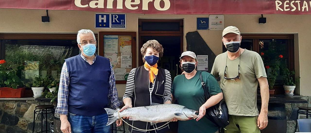 Ángel Fernández y Rosario López, del hotel Canero, junto a los pescadores Leo Peláez y Rogelio González, ayer,  posando con el ejemplar pescado en el Esva. | Rep. de T. C.