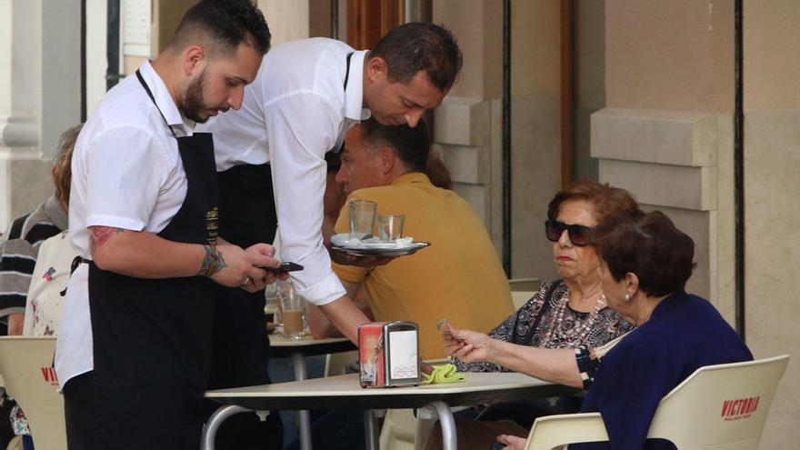 Dos camareros, atendiendo una mesa en el centro de Málaga.