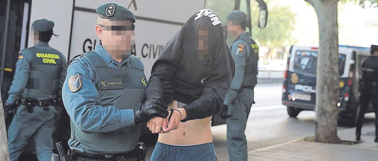 Un detenido en la redada se cubre con la sudadera al conducirle al juzgado.