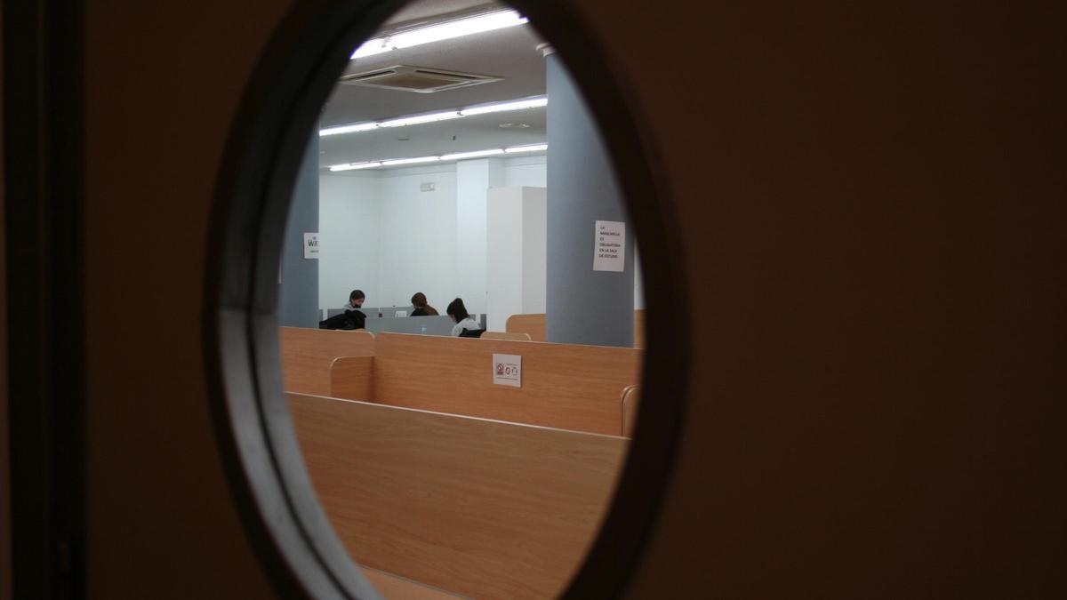 Estudiantes en una sala de estudio de la ciudad a través de uno de los ojos de cristal de su puerta.