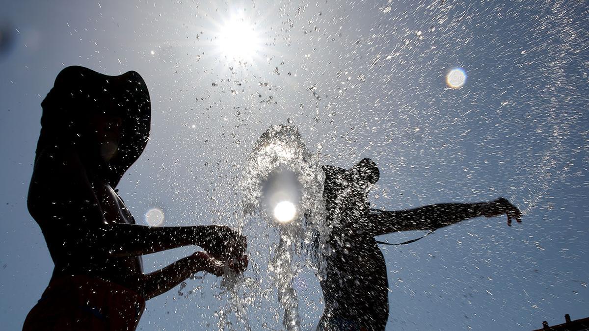 Varios niños se refrescan en la fuente.