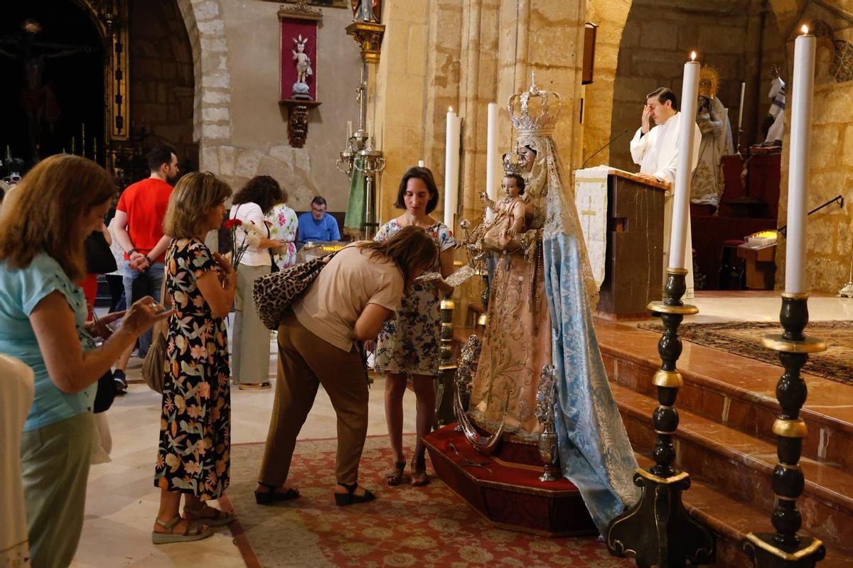 Una mujer besa la mano de la Virgen de los Remedios, en la parroquia de San Lorenzo.